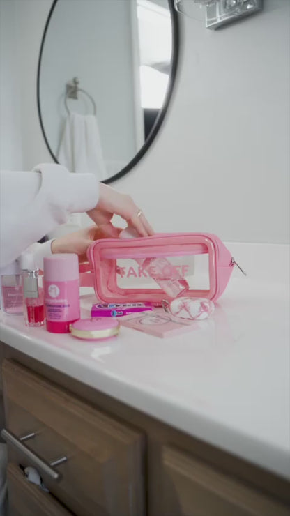 Woman packs the Take OFF Luggage Big Toiletry Pouch with two pressed powder palettes, an eyeshadow palette, a 4 ounce lotion, cotton rounds and two small perfume bottles before zipping her Big Toiletry Pouch and pulling it off the counter by its 1 inc side handle. 
