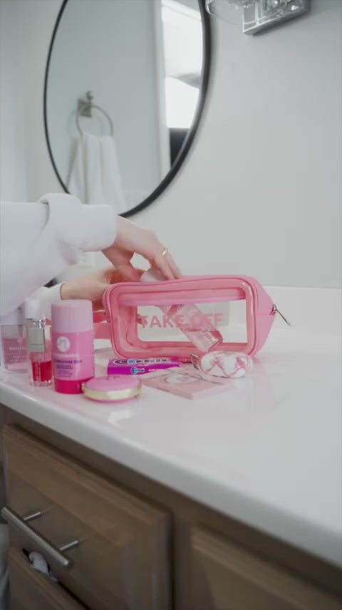 Woman packs the Take OFF Luggage Big Toiletry Pouch with two pressed powder palettes, an eyeshadow palette, a 4 ounce lotion, cotton rounds and two small perfume bottles before zipping her Big Toiletry Pouch and pulling it off the counter by its 1 inc side handle. 